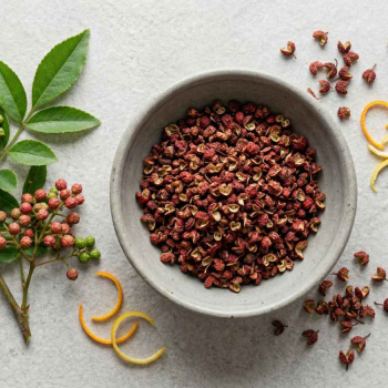 resh and dried Szechuan peppercorns side by side, fresh green and reddish Szechuan pepper clusters on small branches with leaves