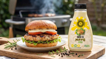 barbecue food scene with a juicy grilled chicken burger on a toasted brioche bun, crisp lettuce, tomato slices and a generous drizzle of creamy mayonnaise sauce, Natural Spices Nice-to-Mayo bottle clearly visible beside the plate