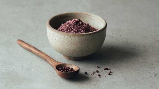 een aardewerk schaaltje gevuld met sumak en een houten lepel met gedroogde sumak bessen